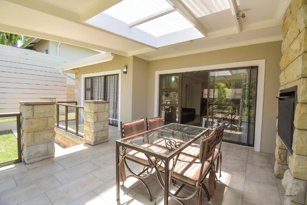 a conservatory with a glass table and chairs on a patio at Willow Rest Villas in Clarens