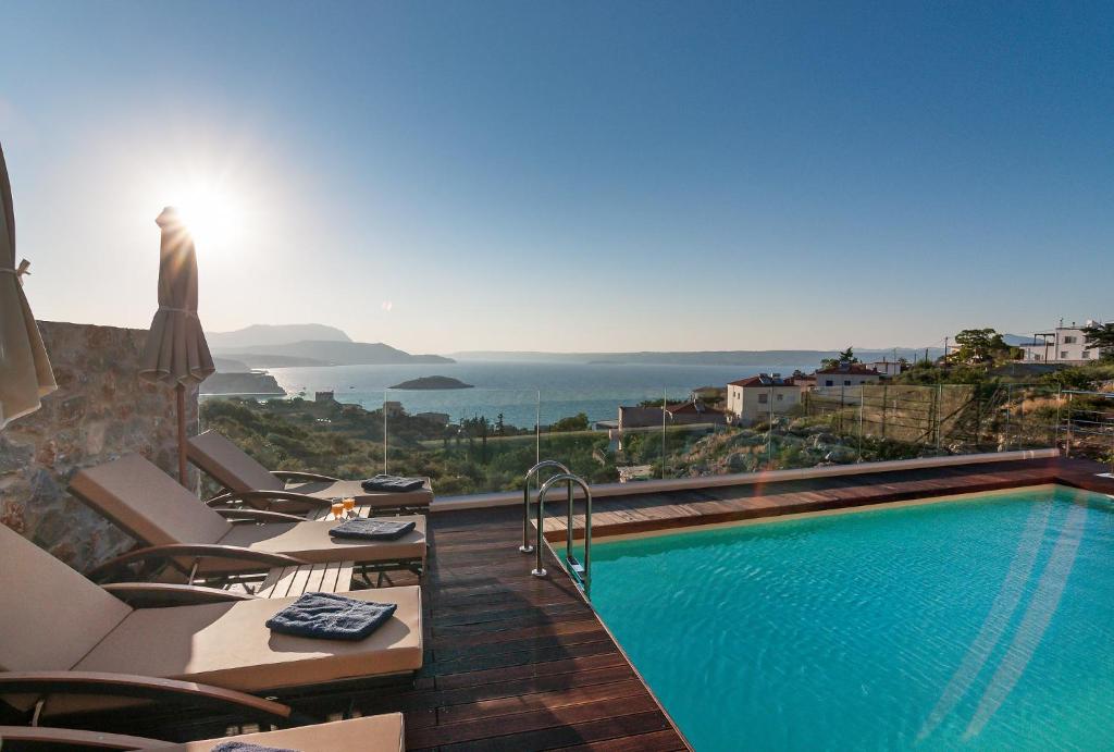 una piscina con sillas y vistas al océano en Villa Vamagia BY APOKORONAS-VILLAS, en Plaka