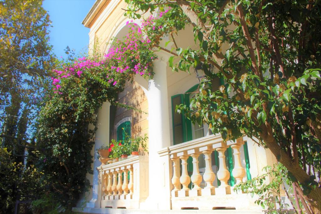 a white building with a balcony with pink flowers at Alchimia SPA & Centro Benessere in Mesagne