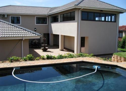 una casa con piscina frente a una casa en Avalon Guest House, en Amanzimtoti