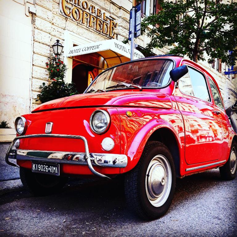 an old red car parked in front of a store at Hotel Coppede' in Rome