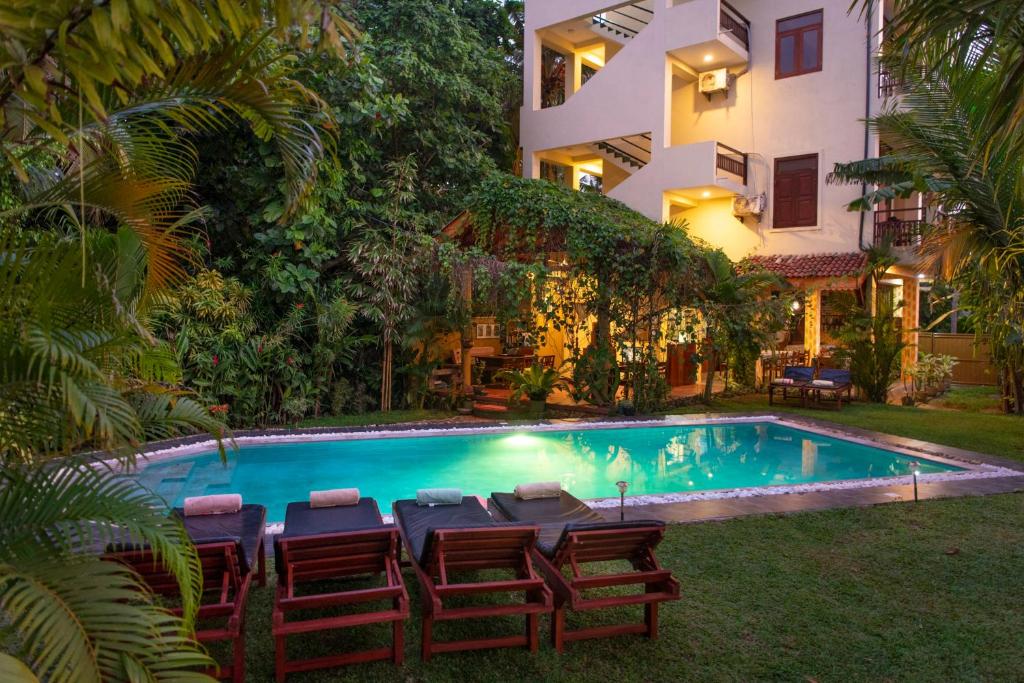 a swimming pool with chairs and a building at Hotel Finlanka in Hikkaduwa