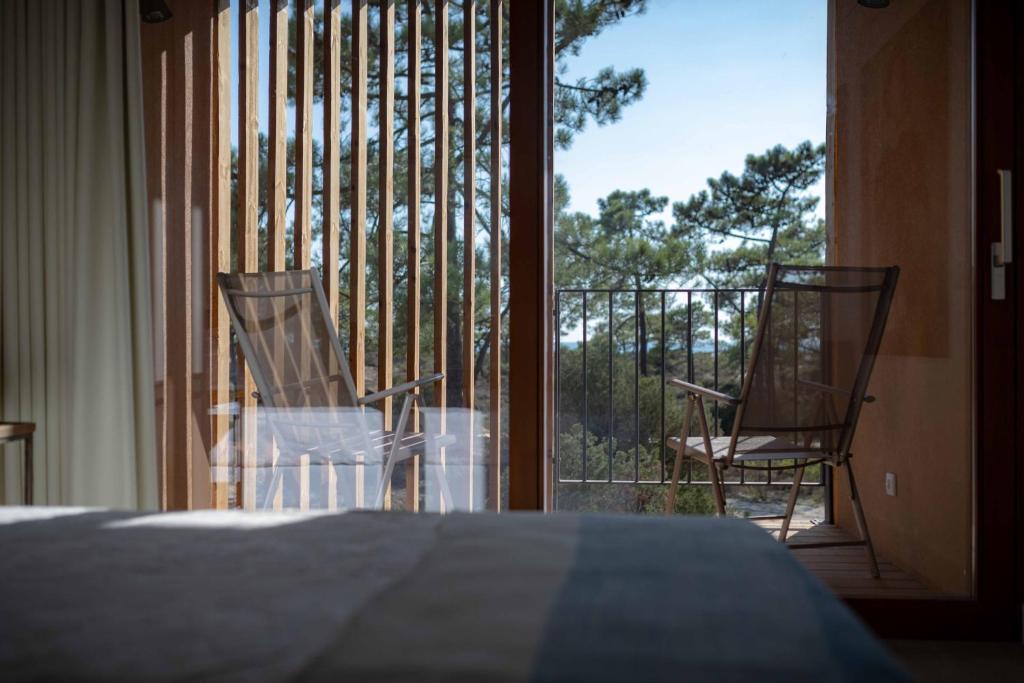 a bedroom with a bed and two chairs on a balcony at Pestana Troia Eco-Resort & Residences in Troia