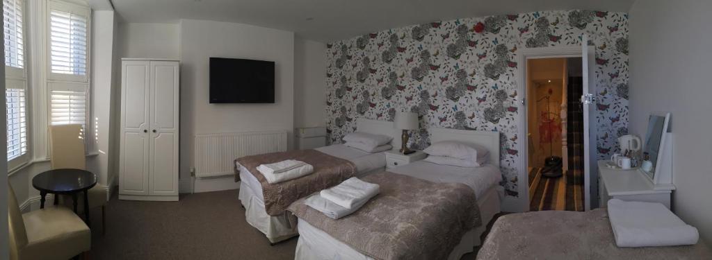 a hotel room with two beds and a television at Acacia Villas Guest House in Guildford