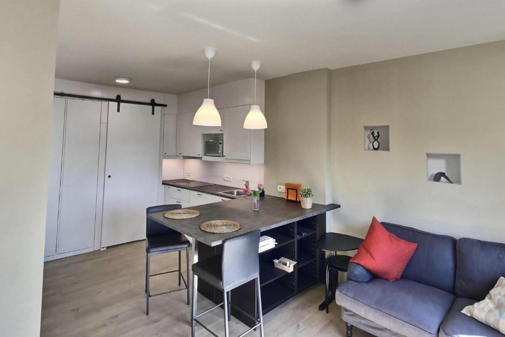 een keuken en een woonkamer met een tafel en een bank bij Studio Félicie in Fexhe-le-Haut-Clocher
