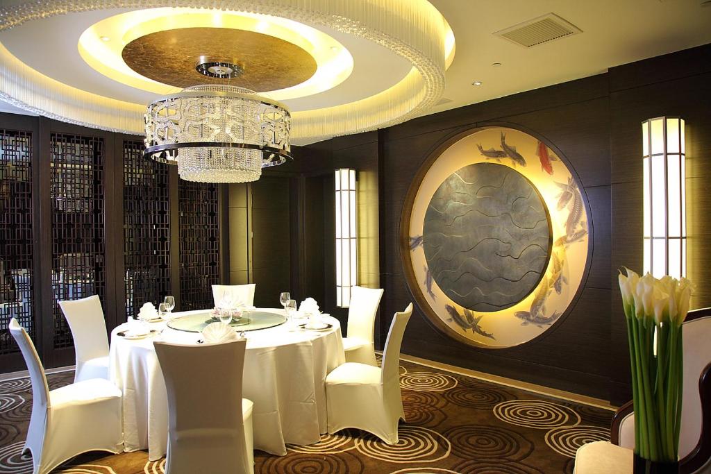 a dining room with a white table and a chandelier at Shanghai Hongqiao Airport Hotel - Air China in Shanghai
