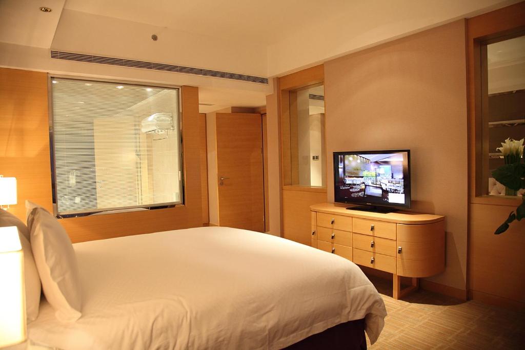 a bedroom with a bed and a flat screen tv at Shanghai Hongqiao Airport Hotel - Air China in Shanghai