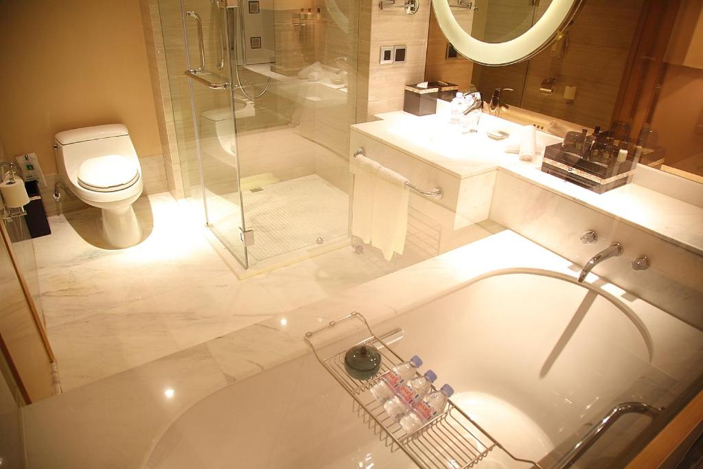 a bathroom with a tub and a shower and a toilet at Shanghai Hongqiao Airport Hotel - Air China in Shanghai
