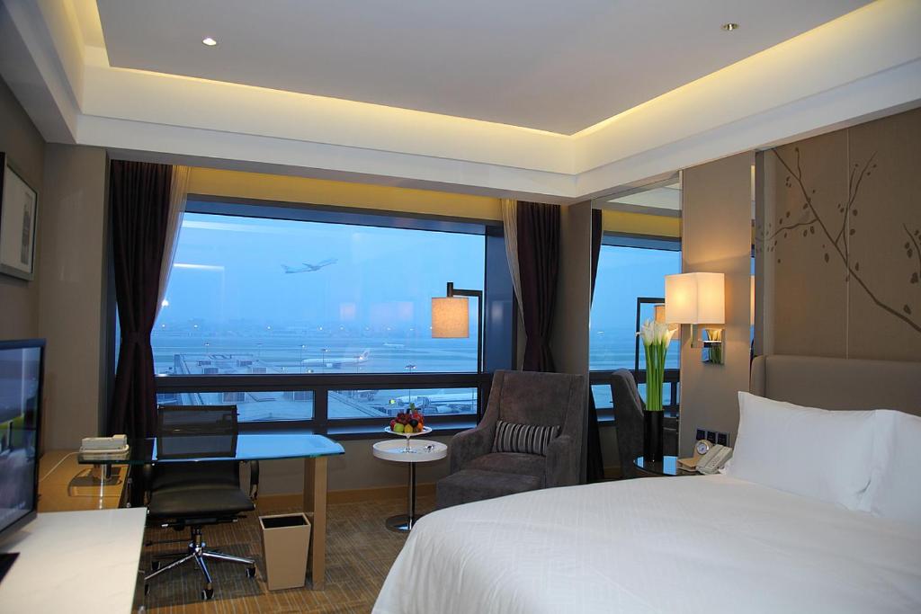 a hotel room with a bed and a large window at Shanghai Hongqiao Airport Hotel - Air China in Shanghai