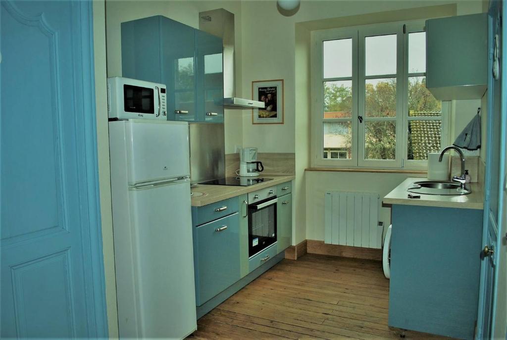 una cucina con armadi blu e frigorifero bianco di Les Cimaises du Couvent a Beaune