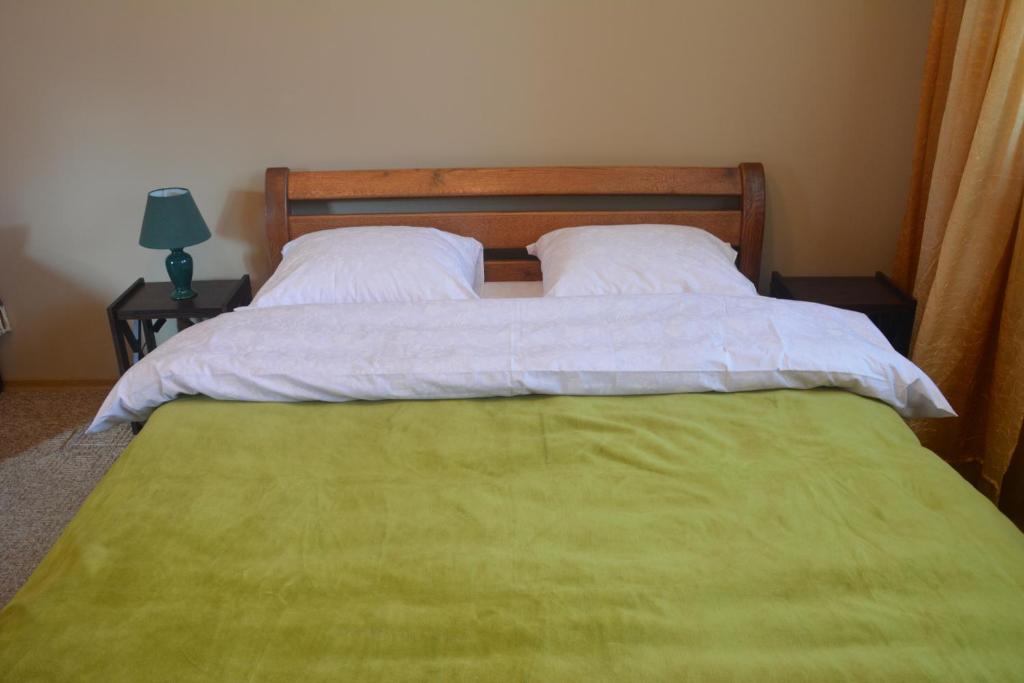 een slaapkamer met 2 bedden met witte lakens en een groene deken bij Sadyba Karpatiya in Jaremtsje