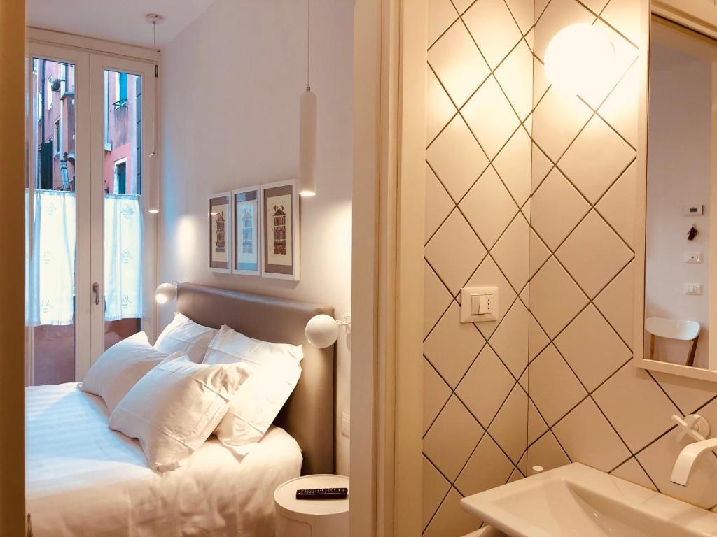 1 dormitorio con cama, espejo y lavamanos en San Marco Design Suites, en Venecia