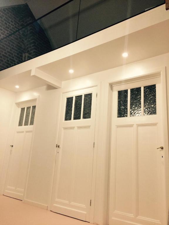 two white garage doors with windows in a room at Nelly in Ypres
