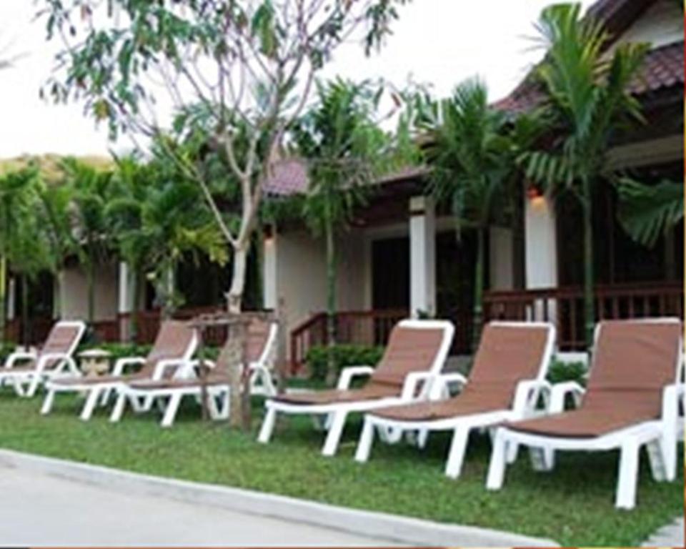a row of lounge chairs in front of a house at Katanoi Resort in Kata Beach