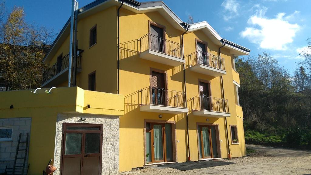 un edificio amarillo con 2 balcones encima en Villa Center appartamenti nel verde in città en Campobasso
