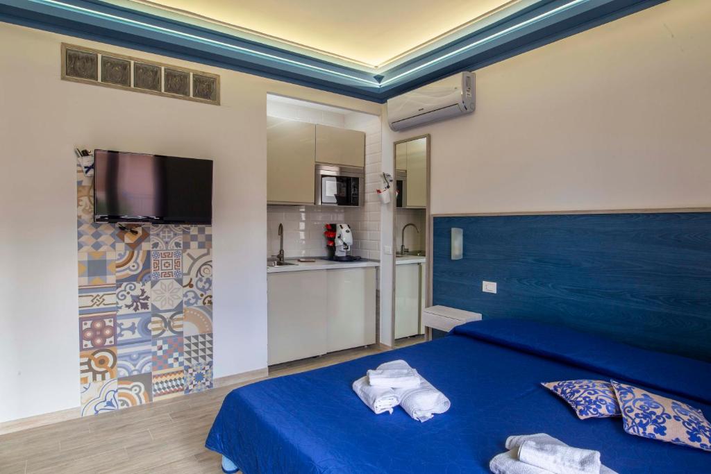 sypialnia z niebieskim łóżkiem i kuchnią w obiekcie Elisir Suite Rooms by Marino Tourist w mieście San Vito lo Capo