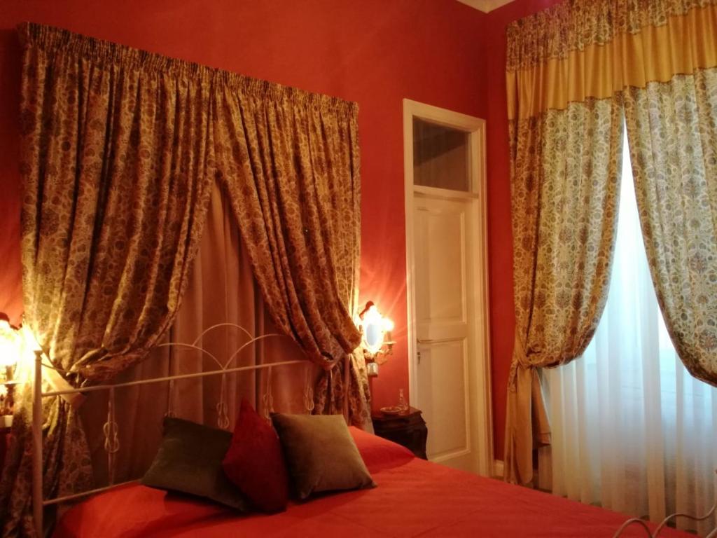 a bedroom with red walls and curtains and a bed at La dimora del giurista in Rossano