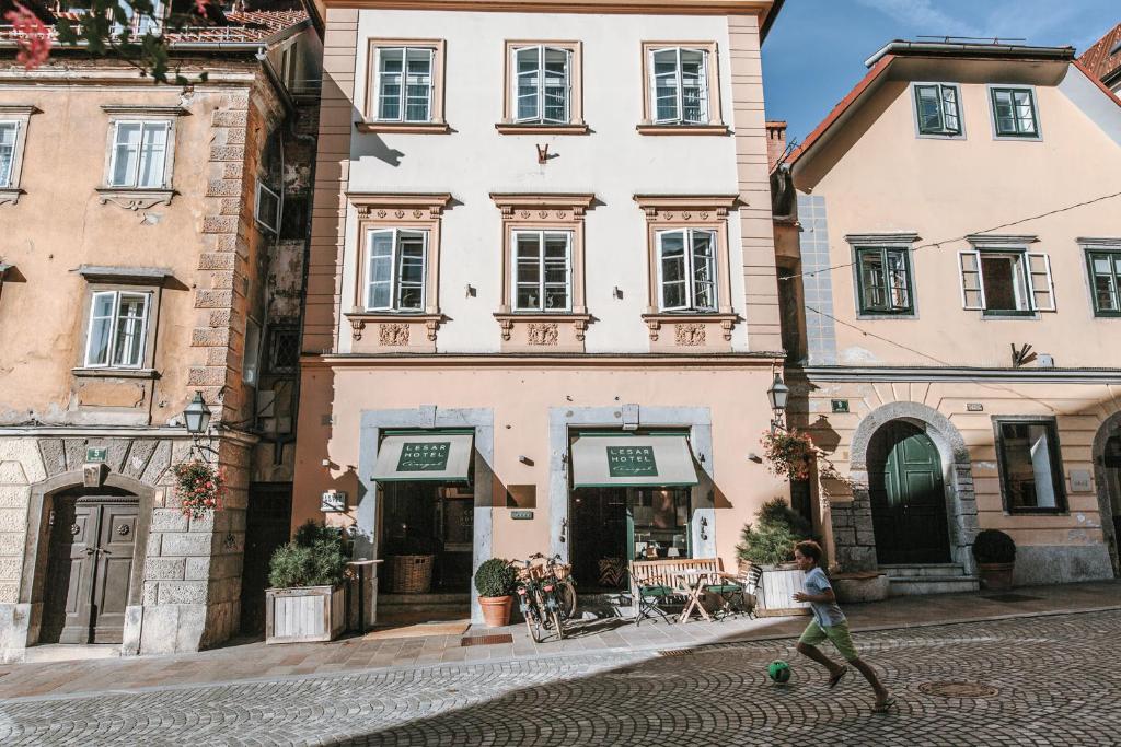 a woman walking down a street in front of a building at Lesar Hotel Angel - Member of Hip Hotels in Ljubljana