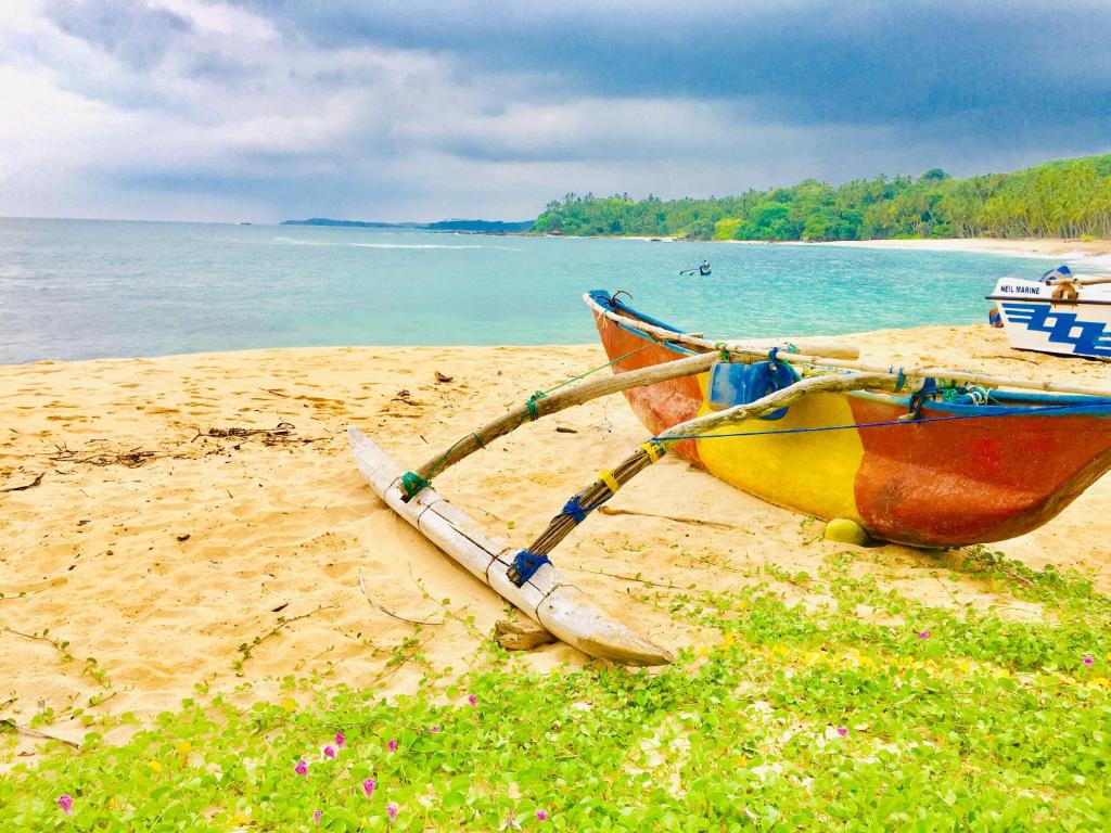 a boat sitting on a beach next to the water at Sea Breeze Garden in Tangalle