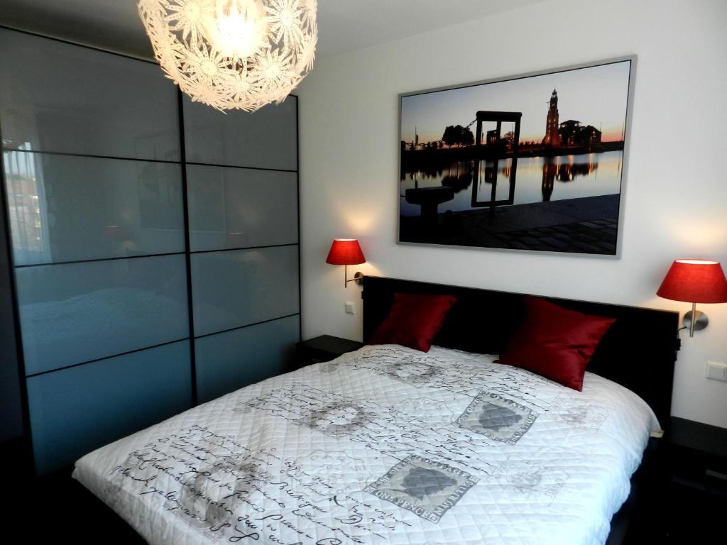 Un dormitorio con una cama con almohadas rojas y una lámpara de araña. en Miramar en Bremerhaven