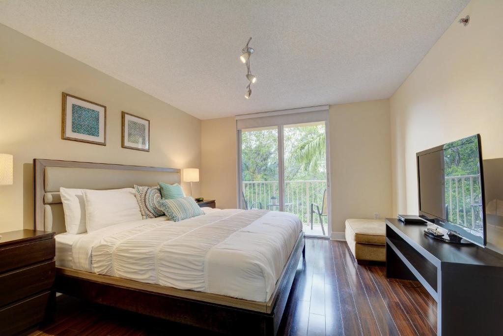 a bedroom with a large bed and a television at Renovated 2/2 Unit at Yacht Club/Aventura in Aventura