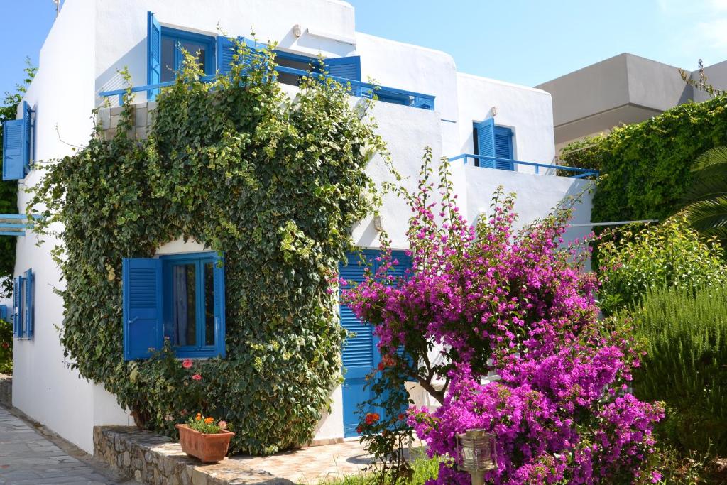 um edifício branco com persianas azuis e flores roxas em Galeana Beach Hotel em Platanes