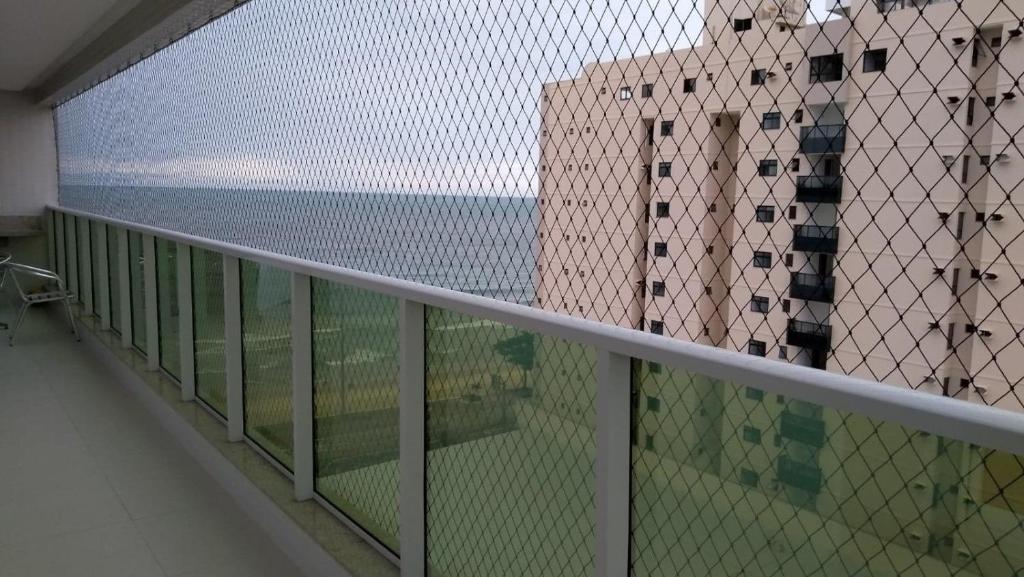 apartamento praia do morro - beira mar في غواراباري: شرفة مطلة على المحيط والمباني