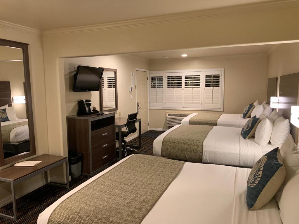 a hotel room with two beds and a television at El Castell Motel in Monterey