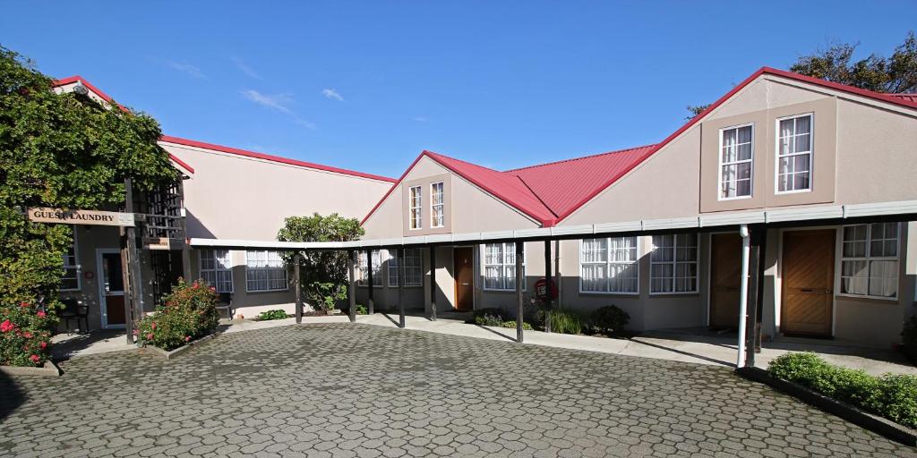 a building with a red roof and a driveway at Balmoral Lodge Motel in Invercargill