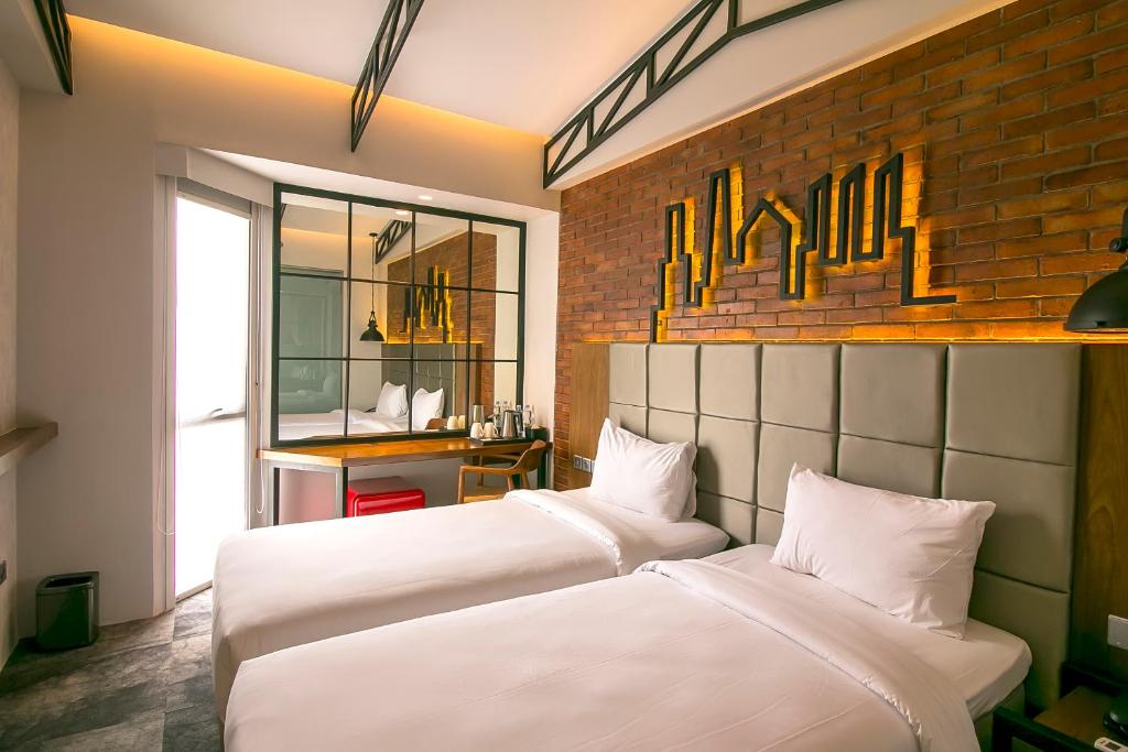 twee bedden in een kamer met een bakstenen muur bij Posto Dormire Hotel in Jakarta