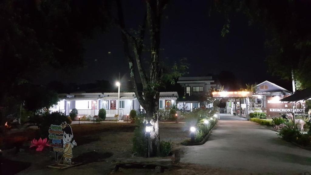 una calle de noche con casas y luces en Moat View, en Sukhothai