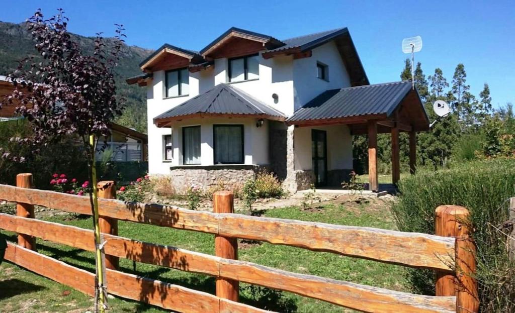 una casa blanca detrás de una valla de madera en Cabaña Lecalau en Lago Puelo