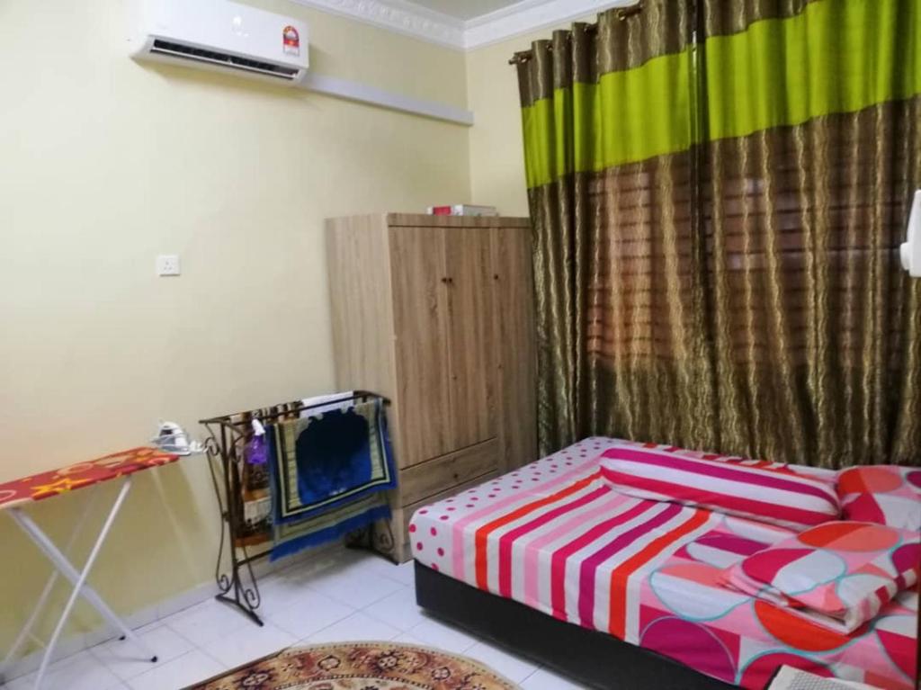 a bedroom with a bed with a colorful blanket at KhainadzMuslim Homestay in Melaka