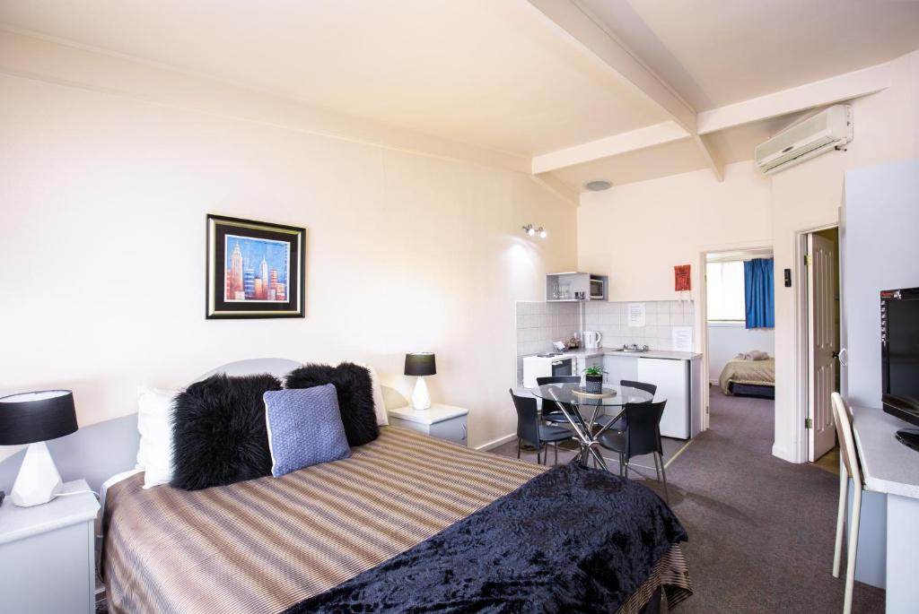 a bedroom with a bed and a small kitchen at Mid City Motel in Mount Gambier