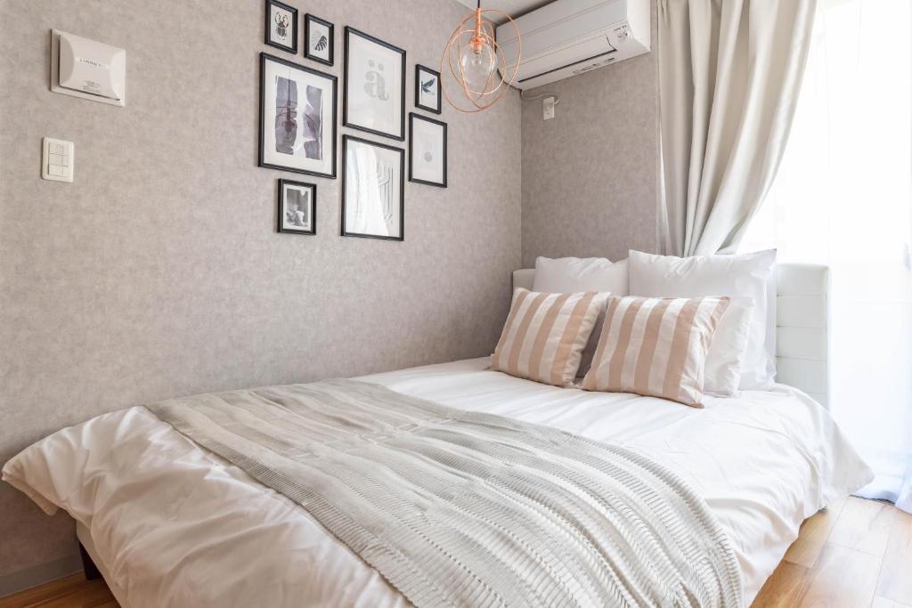 a bedroom with a white bed with pictures on the wall at Exia Daikoku AFP Apartment in Osaka