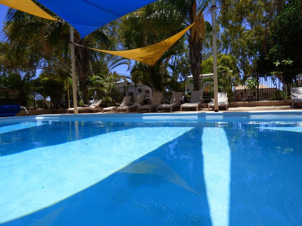 una gran piscina con sillas y una bandera en Discovery Parks - Carnarvon, en Carnarvon