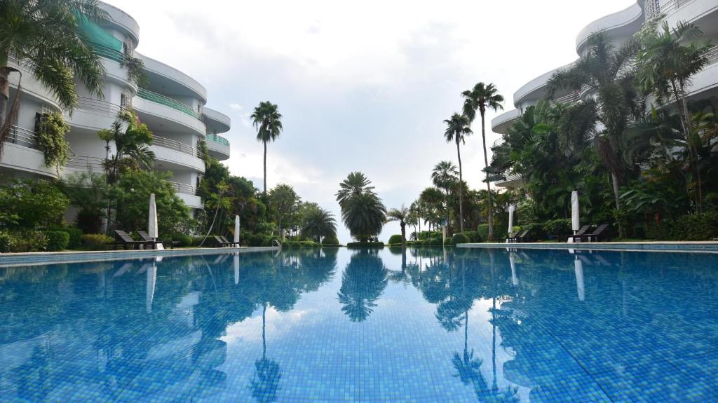 a large swimming pool in front of a building with palm trees at Hua Hin Beachfront Condo in Hua Hin