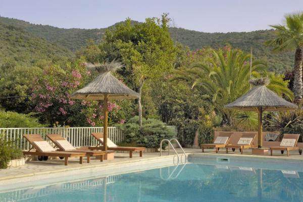 a swimming pool with chairs and umbrellas next to a swimming pool at Résidence Stella Marina in Serriera