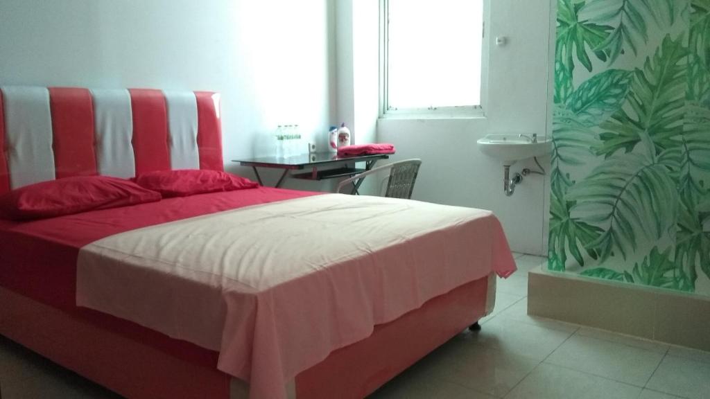 a bedroom with a red and white bed and a window at Uni Inn Semarang - Gunung Pati in Semarang