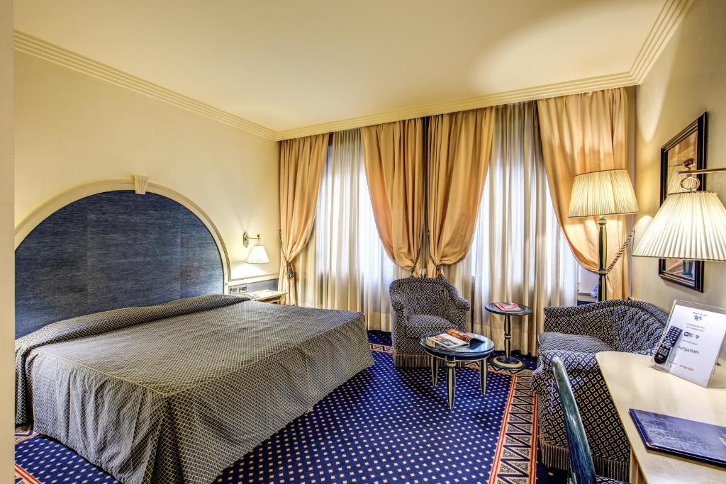 a hotel room with a bed and two chairs at Hotel Auriga in Milan