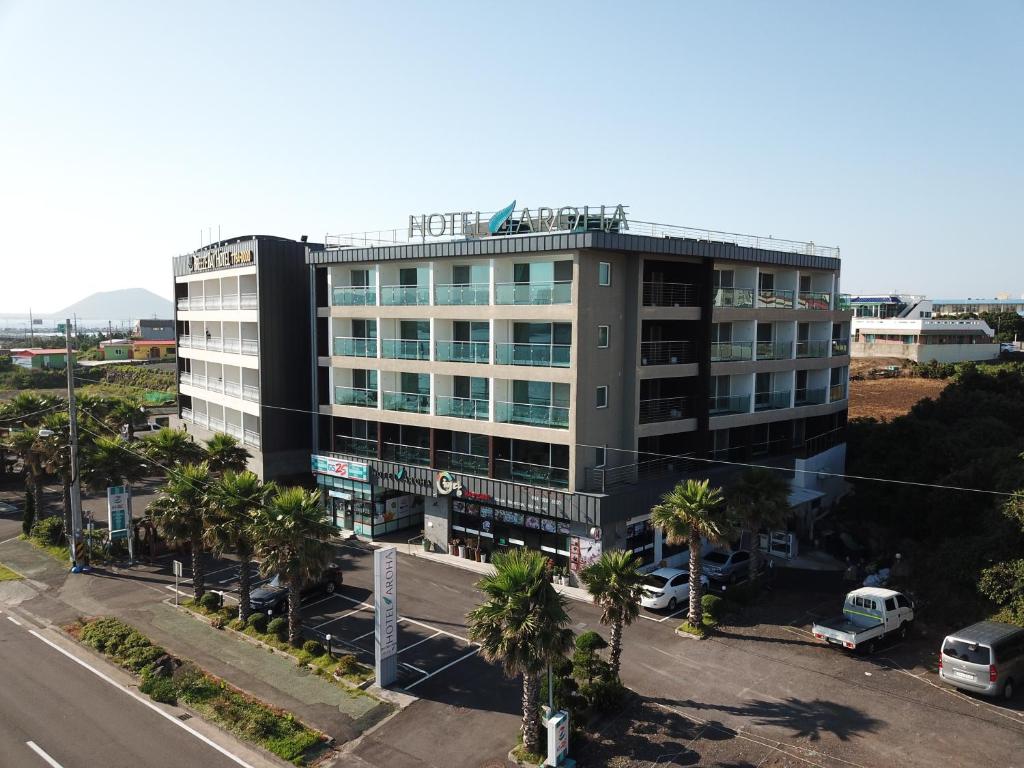 a building with palm trees in front of a street at Hotel Aroha in Seogwipo