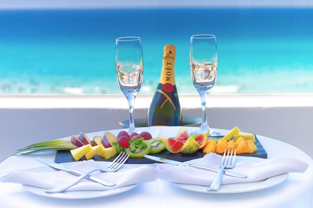 una mesa con dos copas de vino y un plato de fruta en Hotel Maysi, en Playa de Migjorn