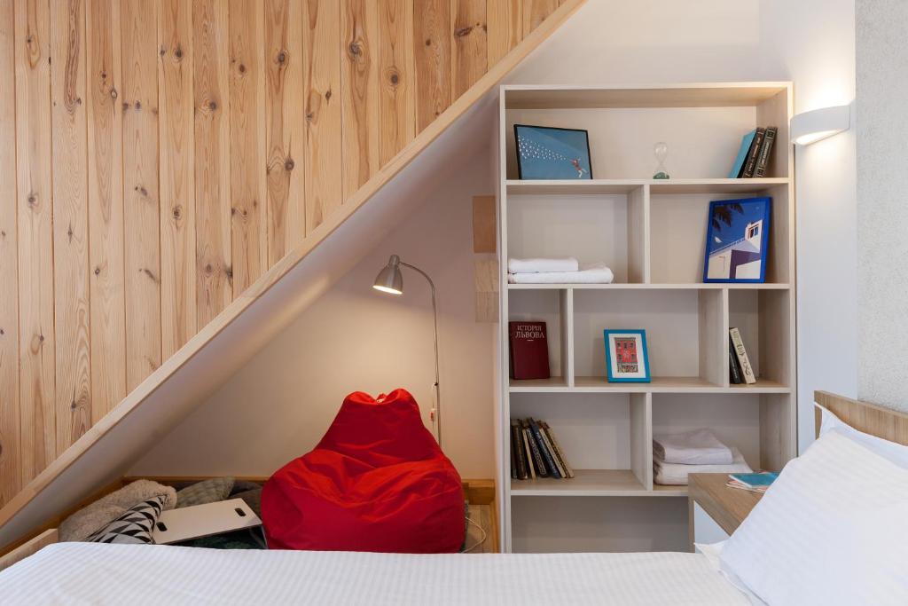 Un dormitorio con una cama con una manta roja sentada debajo de las escaleras en 7 Apartments, en Leópolis
