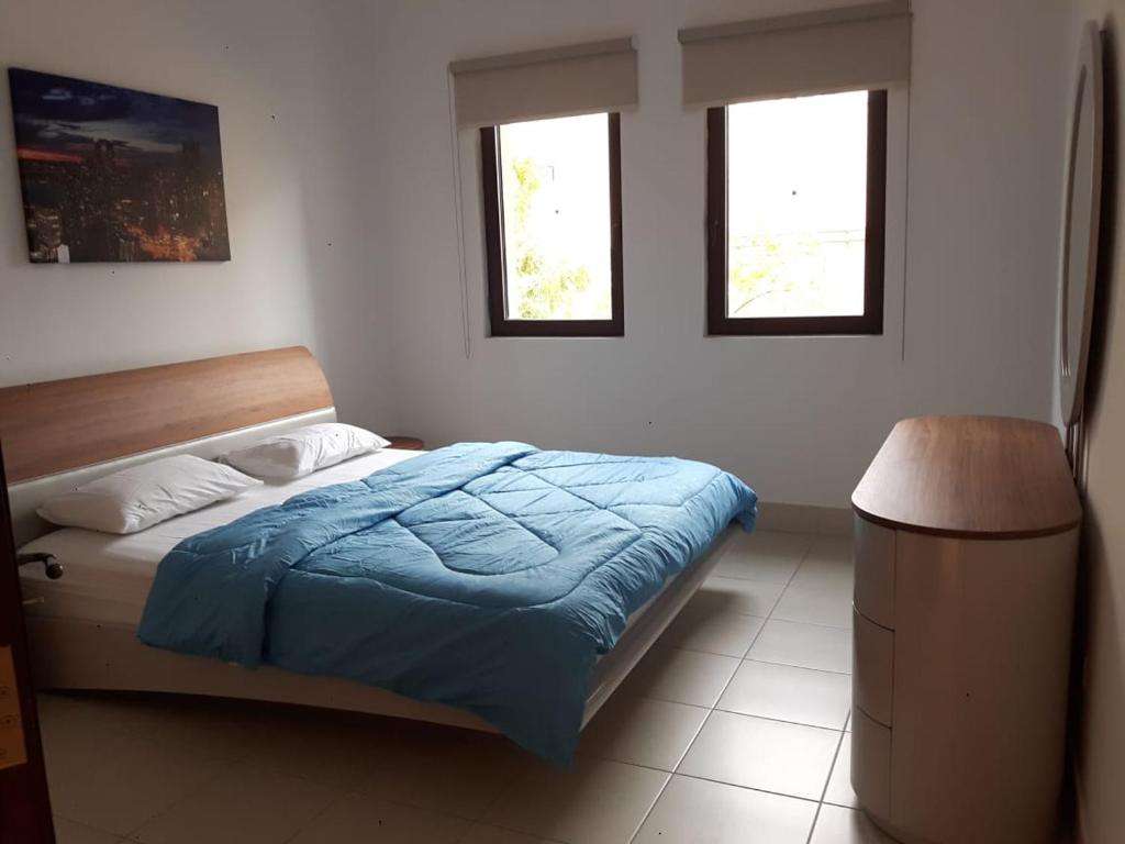 a bedroom with a bed and two windows at Holiday Homes in Dubai