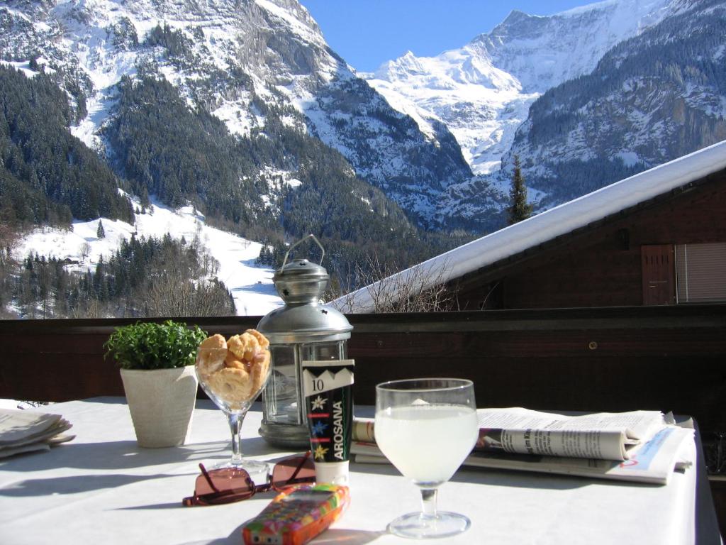 una mesa con una copa de vino y vistas a las montañas en Casa Almis, Grindelwald en Grindelwald