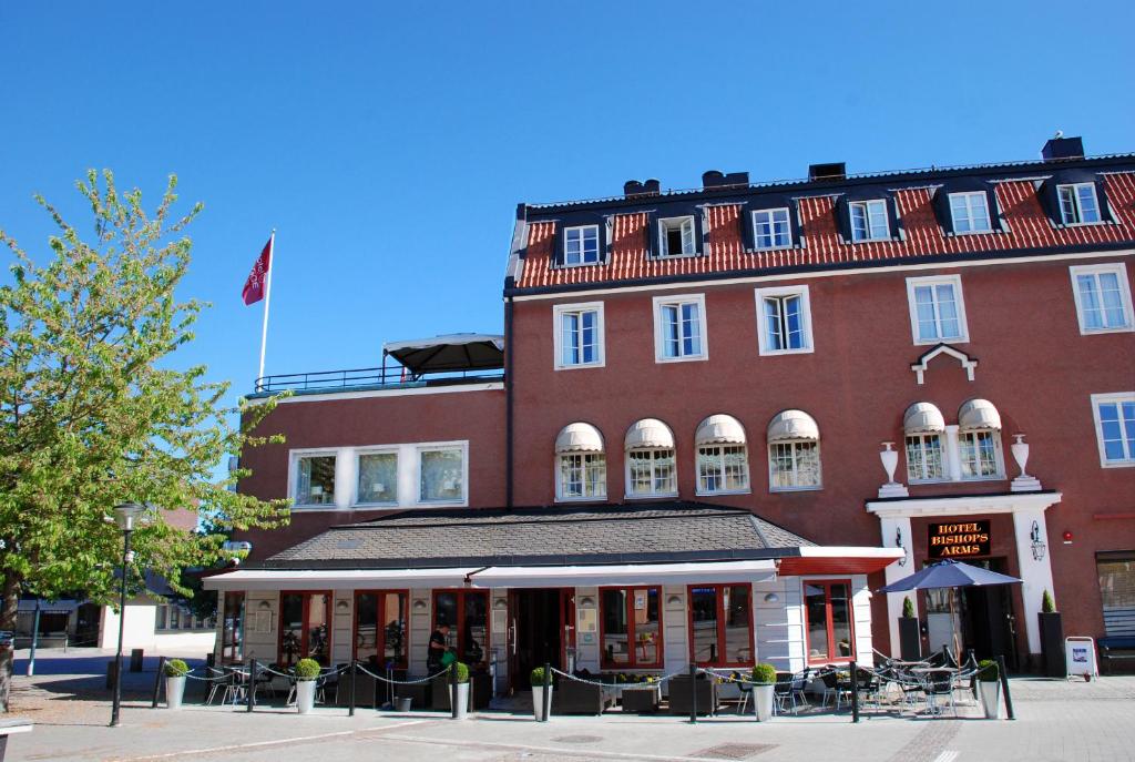 un gran edificio de ladrillo rojo con una bandera. en Hotel Bishops Arms Strängnäs, en Strängnäs