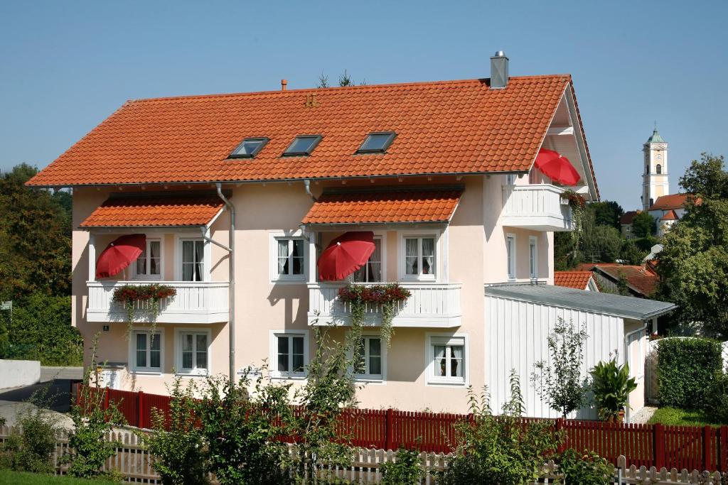 ein weißes Haus mit roten Dächern und einem roten Zaun in der Unterkunft Ferienwohnungen Eleonore in Bad Birnbach