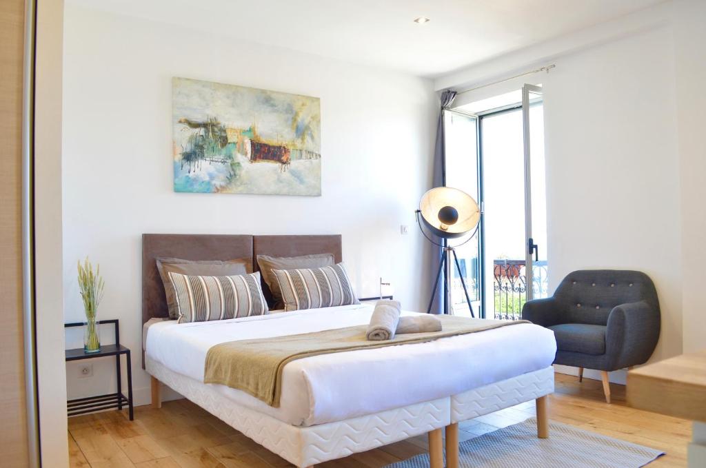une chambre avec un grand lit et une chaise dans l'établissement Studio Biarritz - rénové et moderne - au calme - centre ville - tout à pied, à Biarritz