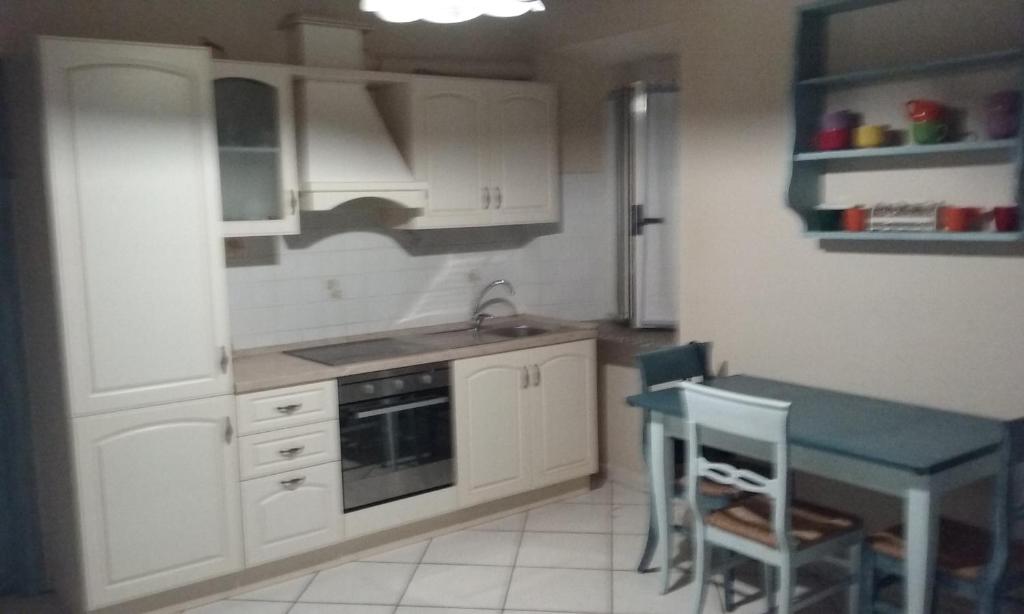 a kitchen with white cabinets and a table and a sink at La casina di Silverio in Rio Marina