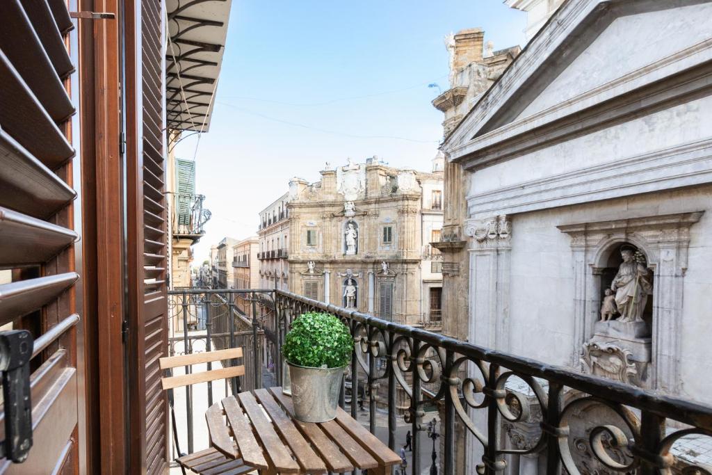a balcony with a wooden chair and a potted plant at Quattro Canti Charming Flat in Palermo